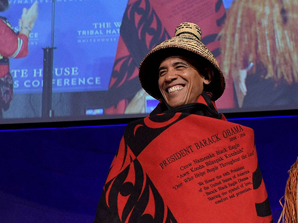 President Barack Obama is wrapped in a custom tribal robe, woven for the Swinomish Tribe, at the Tribal Nations Conference in Washington, D.C., 2016.